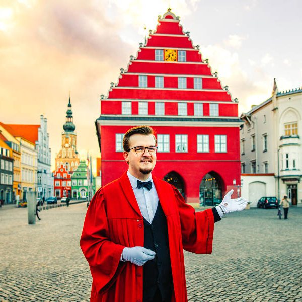 Im Talar gewandeter Stadtführer vor dem Rathaus